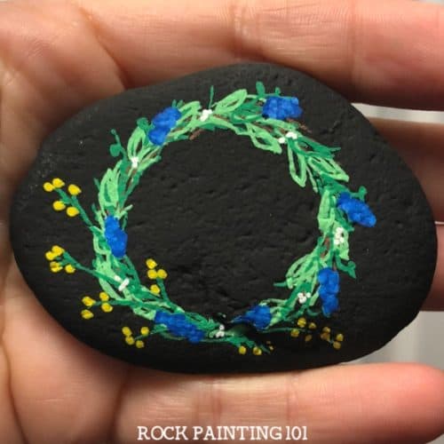 This spring wreath painted rock is a fun and simple! Check out how to draw a wreath with paint pens and be amazed at how simple this stone painting idea is!