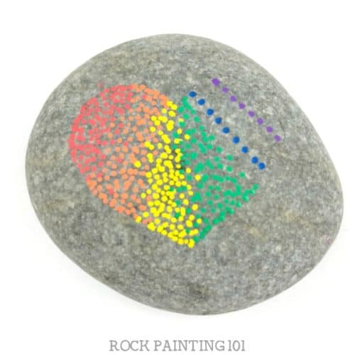 These rainbow pointillism heart rocks are beautiful and fun to create. They are perfect for people who love the dot painting look but don't have the steady hand for its perfection. #rainbow #pointillism #rockart #heartrock #paintedrocks #rockpaintingforbeginners #stonepainting #rockpainting101