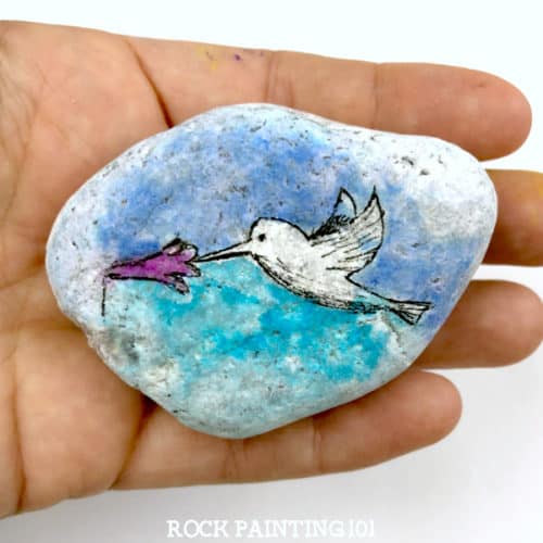 Paint a beautiful hummingbird using a simple technique. Create the look of watercolors without the difficulty and you'll paint a beautiful rock. #watercolor #hummingbird #howtopaintrocks #stonepainting #paintedrocks #rockart #howtopaint #rockpainting101