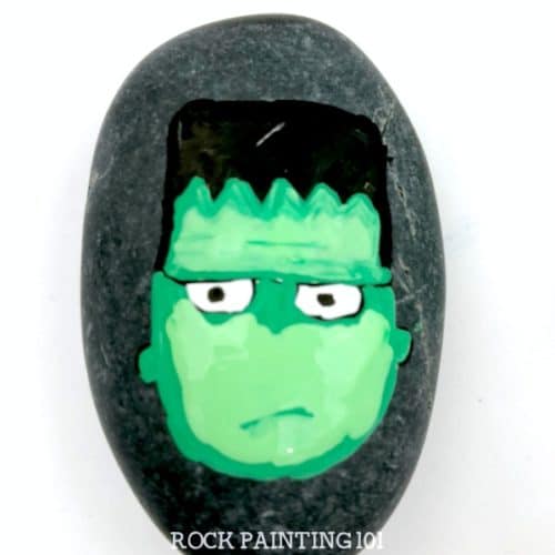 Paint a Frankenstein's monster for a spooky and fun Halloween rock painting idea. He's cute and creepy and perfect for kids to find while their trick or treating! #frankenstein #frankentsteinsmonster #halloweenrockpaintingideas #halloween #stonepainting #monsterrocks #howtopaintrocks #howtodraw #rockpainting101