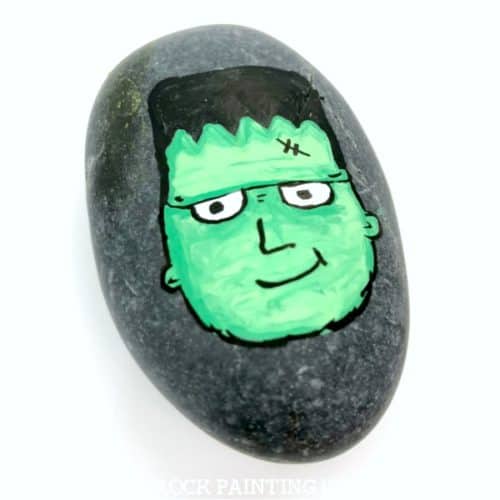 Paint a Frankenstein's monster for a spooky and fun Halloween rock painting idea. He's cute and creepy and perfect for kids to find while their trick or treating! #frankenstein #frankentsteinsmonster #halloweenrockpaintingideas #halloween #stonepainting #monsterrocks #howtopaintrocks #howtodraw #rockpainting101