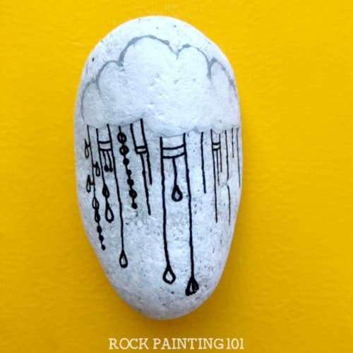 This fun raincloud zendangle painted rock is a great rock painting idea for beginners or for those looking to improve their skill. #zendangle #raincloud #kindnessrocks #rockpainting #paintedrocks #rockart #howtozendangle #dangles #rockpainting101