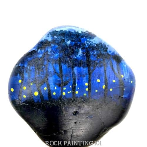 This fireflies rock painting idea is perfect for decorating your night painted rocks. Create layers of trees to make your rock stand out and look amazing. #fireflies #lighteningbugs #night #rockpainting #howtopaintrocks #stonepainting #rockpainting101