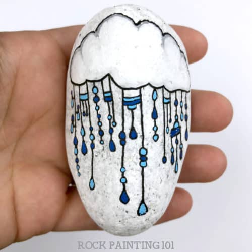 This fun raincloud zendangle painted rock is a great rock painting idea for beginners or for those looking to improve their skill. #zendangle #raincloud #kindnessrocks #rockpainting #paintedrocks #rockart #howtozendangle #dangles #rockpainting101