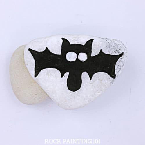 Learn how to paint a bat to make these spooky and fun Halloween painted rocks. Follow along with these step by step instructions and you'll be hiding bat painted rocks in no time! #batrocks #paintedrock #howtopaintabat #halloweenpaintedrocks #rockpaintingideas #stonepainting #rockpainting101