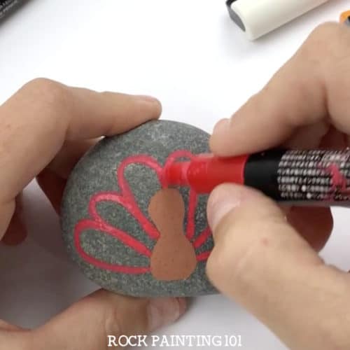 Paint a turkey onto a rock for a fun Thanksgiving rock painting idea. These rocks will look perfect on your Thanksgiving table or hiding around your city! #turkeyrocks #turkeypaintedrock #thanksgivingrock #fallpaintedrocks #howtopaintaturkey #thanksgivingdinnertable #rockpainting101