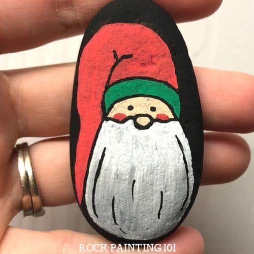 This Christmas gnome rock painting idea is a fun way to paint rocks during the holidays. Learn how to draw a gnome onto a rock with step by step instructions and a video tutorial. #christmasgnome #holidaygnome #christmasrocks #howtodrawagnome #holidayrockpainting #rockpainting101