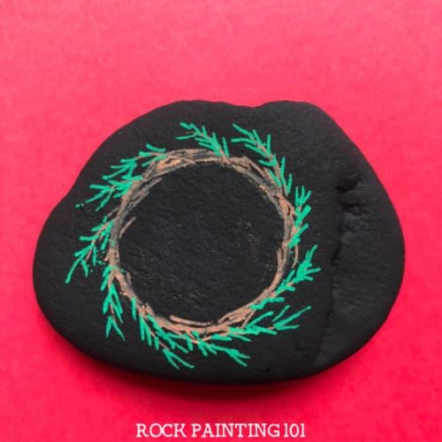 This fun Christmas wreath painted rock is a fun wreath craft that you can use as stocking stuffers, Christmas decor, or to hide around your city. Check out the video tutorial to learn how to paint a wreath. #christmaswreath #wreathcraft #christmaspaintedrocks #rockpaintingforbeginners #rockpainting101