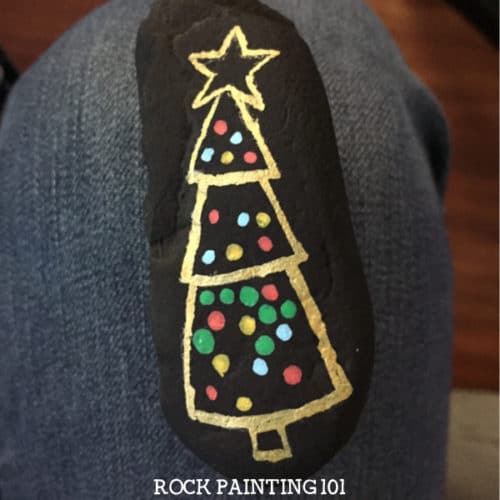 Create this fun dotted Christmas tree rock with this fun video tutorial. This Christmas rock is perfect for beginners and is sure to bring smiles this holiday season! #dotted #christmastree #christmasrocks #paintedrocks #dottedrocks #dotpainting #forbeginners #rockpainting101