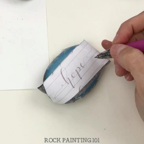 How to use carbon paper to hand letter on rocks. Using this simple supply and practice sheets, you will be hand lettering your painted rocks like a pro! #handlettering #carbonpaper #easy #tutorial #kindnessrocks #holidayrocks #hope #howtopaintrocks #rockart #paintedrocks #rockpainting101