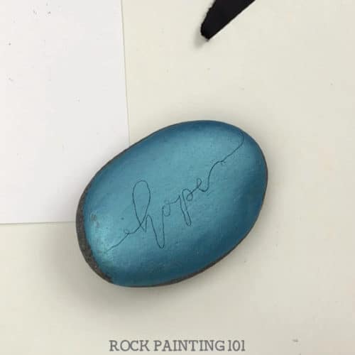 How to use carbon paper to hand letter on rocks. Using this simple supply and practice sheets, you will be hand lettering your painted rocks like a pro! #handlettering #carbonpaper #easy #tutorial #kindnessrocks #holidayrocks #hope #howtopaintrocks #rockart #paintedrocks #rockpainting101