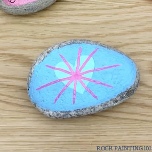 These radial heart painted rocks are perfect for giving to loved ones or hiding around your city! They make amazing kindness rocks! #rockpainting101