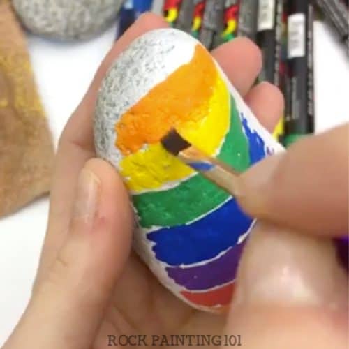 Create beautifully blended rainbows using paint pens. Step by step tutorial for rock painting beginners.
