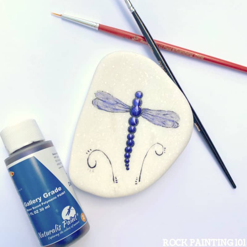 In today's tutorial we are teaching you how to paint dragonfly rocks. This tutorial is perfect for the rock painting beginner and features a beautiful color shift paint from Naturalis Paint that really makes these dragonflies sparkle!
